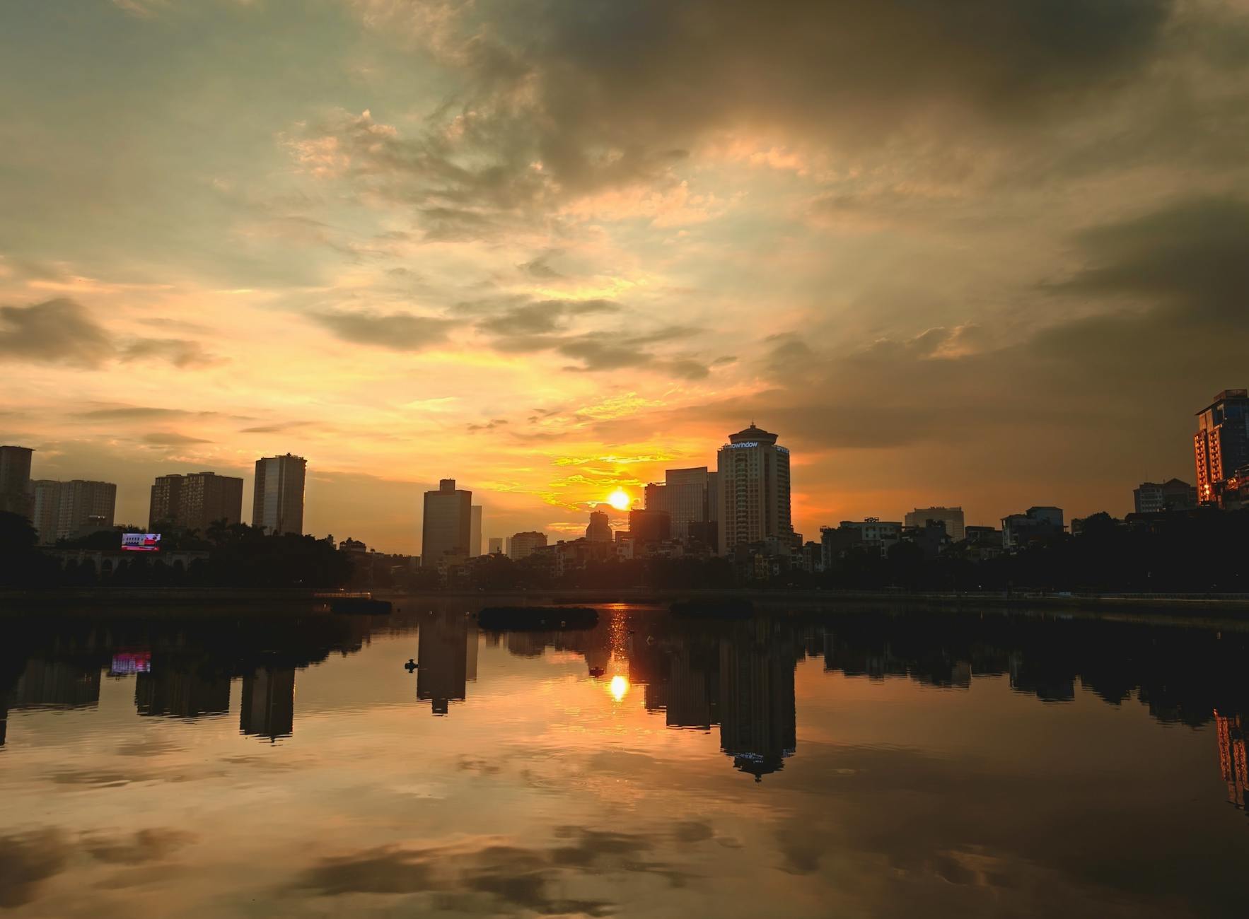 Zachód słońca nad miejską panoramą odbijający się w spokojnej wodzie