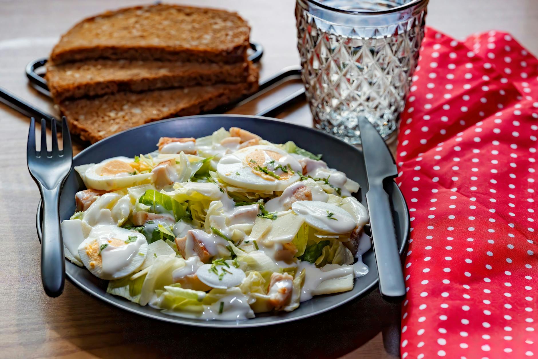 Sałatka Cezar z kurczakiem, jajkiem i pieczywem na drewnianym stole