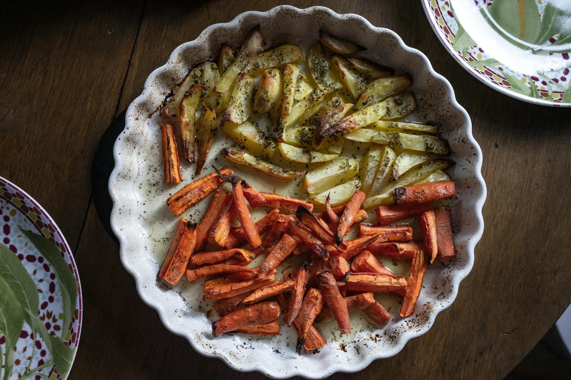 Pieczone ziemniaki i marchew na talerzu z przyprawami z góry