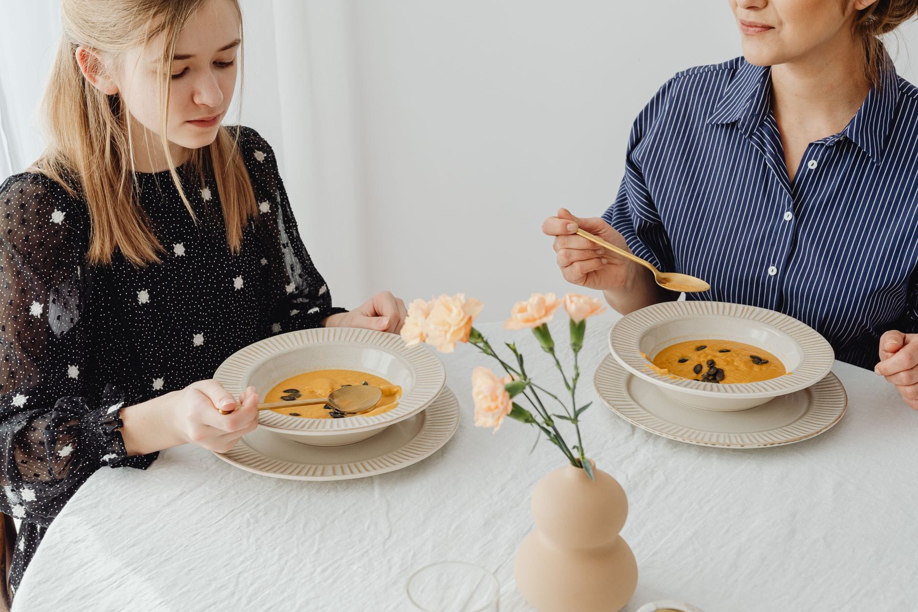 Szybka zupa z tortellini: 15 minut i masz obiad dla całej rodziny Dwie kobiety jedzą domową zupę dyniową przy udekorowanym stole
